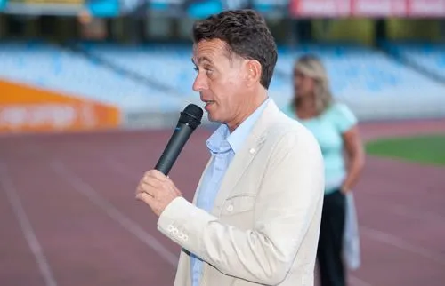 carlos-bengoa Carlos Bengoa hablando por micrófono en un estadio con pista de atletismo.