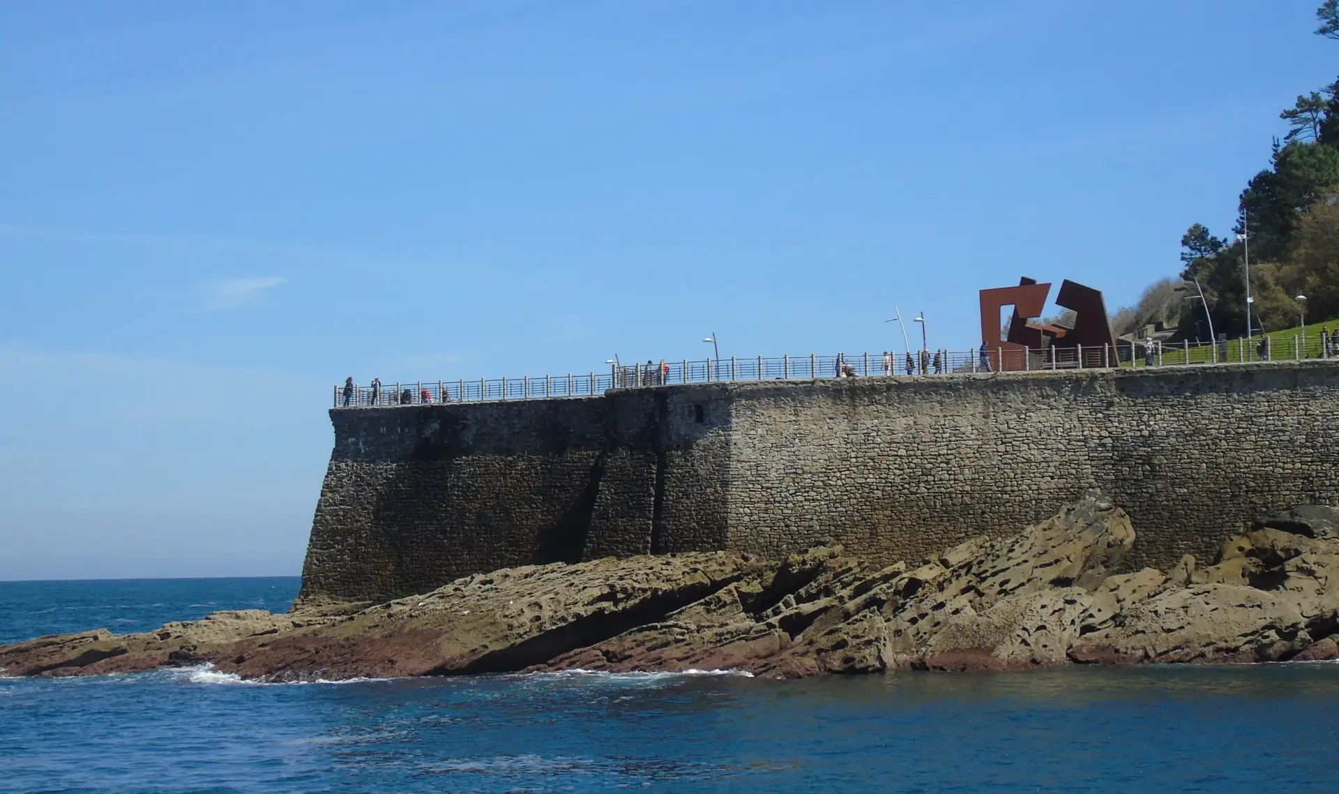 vista-mar-paseo-nuevo-donostia-escultura-chillida Paseo Nuevo de Donostia donde con personas paseando cerca de la escultura de Chillida en el propio paseo.